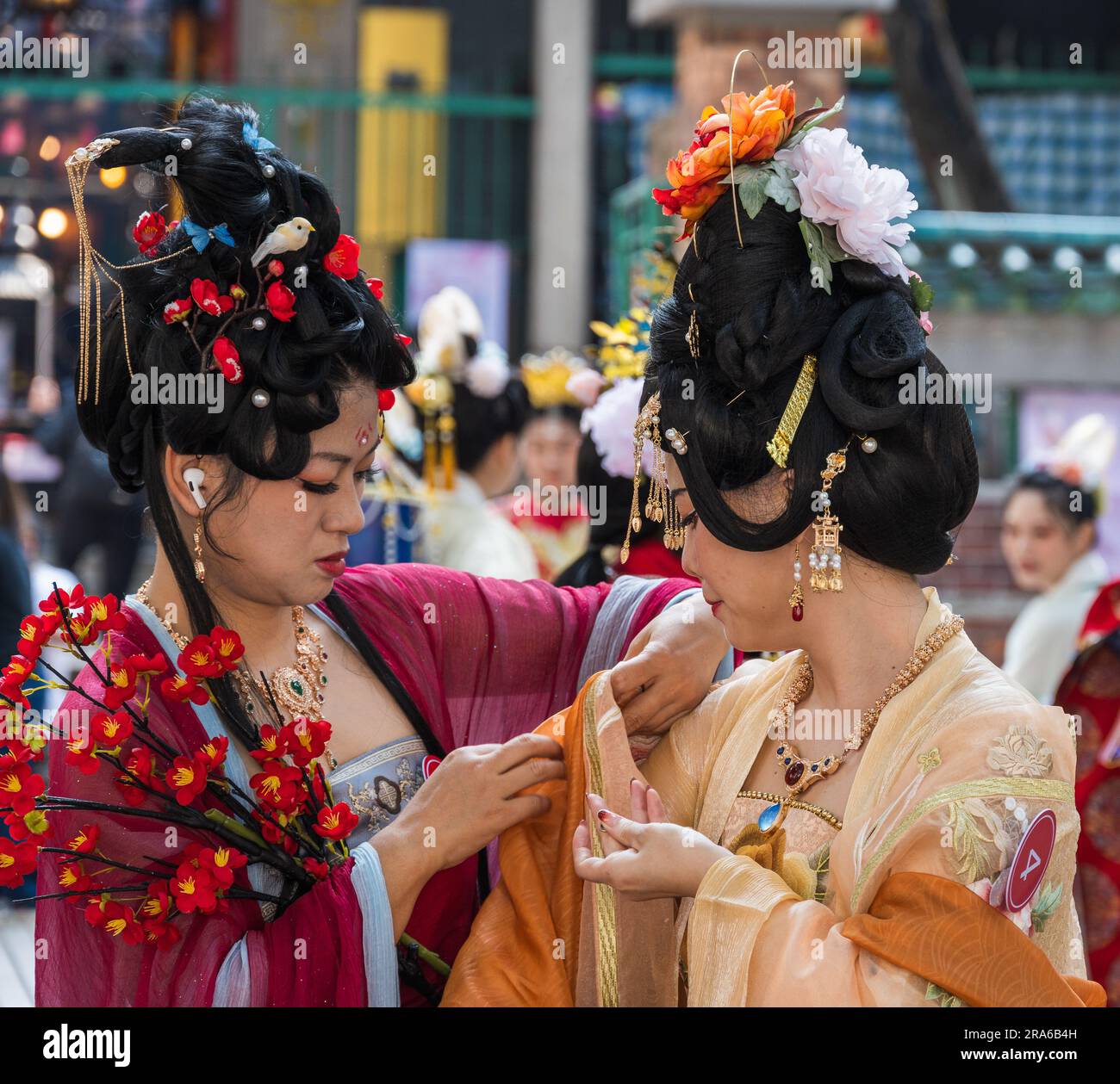 Hong Kong, Chine -- 11 mars 2023. Une femme chinoise aide un autre modèle avec sa tenue de mariage. Banque D'Images