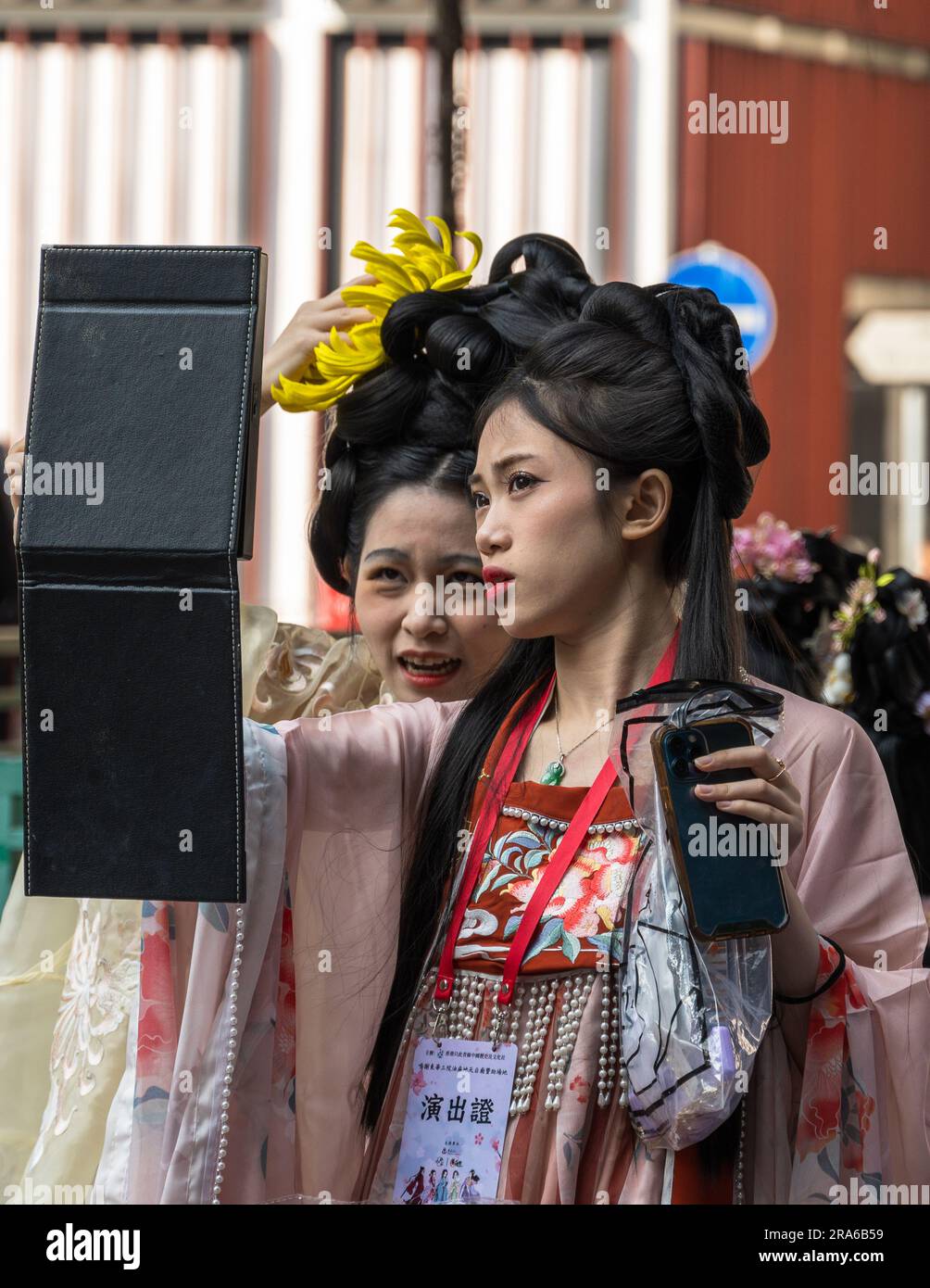 Hong Kong, Chine -- 11 mars 2023. Deux jeunes femmes portant des vêtements de mariage chinois traditionnels se examinent dans un miroir. Banque D'Images