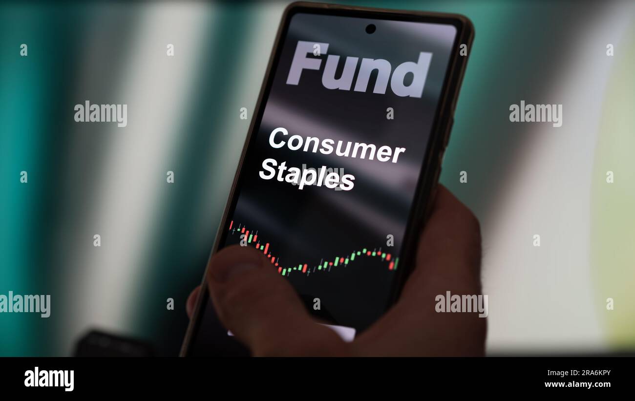 Un investisseur analyse le fonds etf de base de consommation sur un écran. Un téléphone montre les prix des actions de base de consommation Banque D'Images