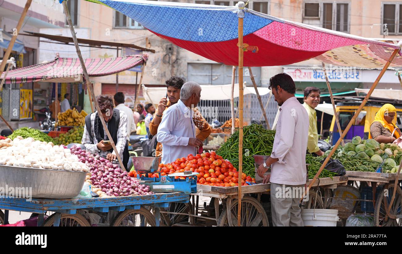 Beawar, Rajasthan, Inde, 1 juillet 2023: Les clients indiens marchandes pour les prix avant d'acheter de la tomate sur un marché de Beawar. Les prix des légumes ont grimpé en flèche dans toute l'Inde. Prix de détail de la tomate au RS 100-120/kg, de l'ail au RS 180-200/kg et du gingembre au RS 240-300/kg dans de nombreuses régions du pays. Banque D'Images