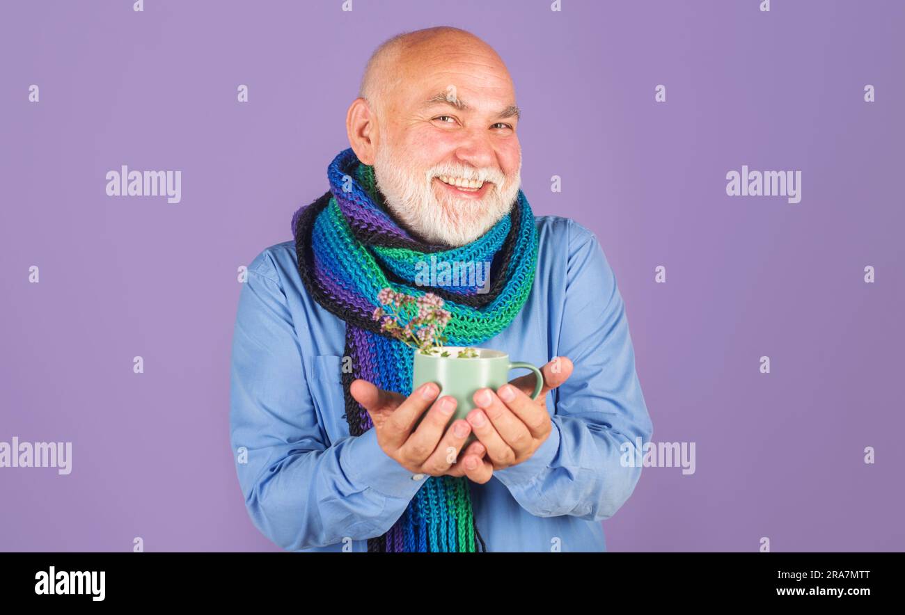 Homme souriant avec du thé de médecine. Homme malade boit tisane de marjoram sauvage origan herbe médicale. Homme malade avec thé santé dans la tasse. Plantes alternatives Banque D'Images