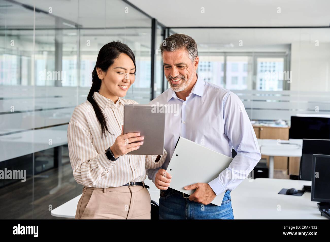 Deux employés professionnels heureux utilisant une tablette numérique au bureau. Banque D'Images