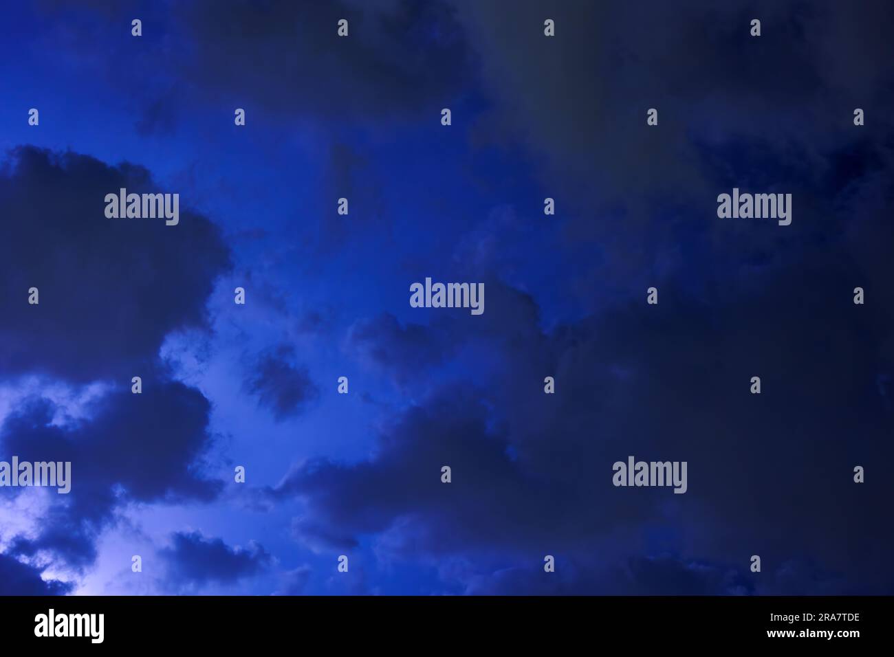 Les nuages se déplacent rapidement à travers le ciel sombre de nuit, les éclairs de lumière de la tempête qui s'approche les éclairent. Banque D'Images