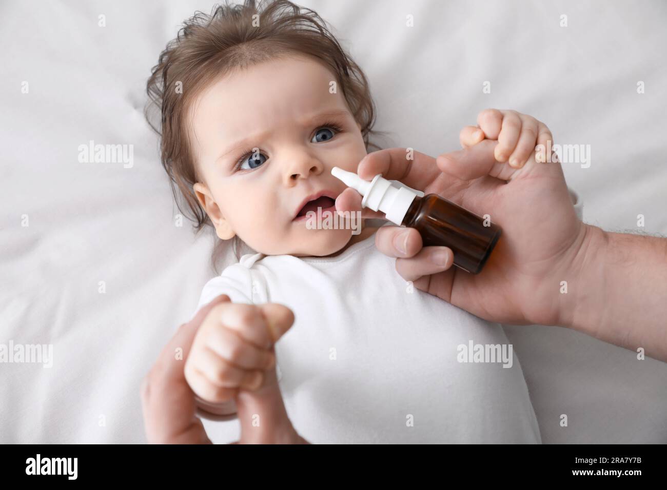 Père prenant soin de bébé souffrant de nez qui coule dans le lit, vue de dessus Banque D'Images