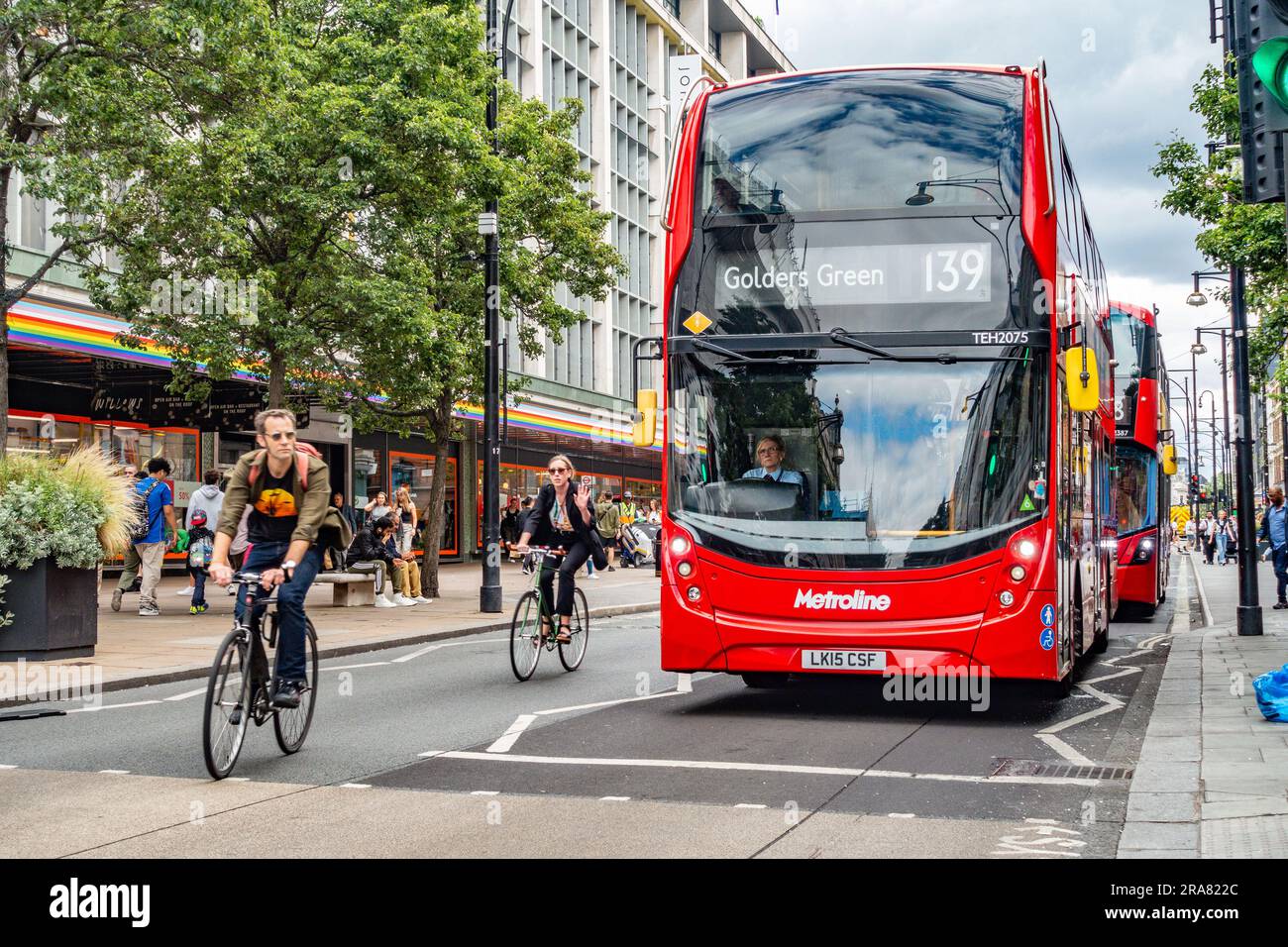 Le non 139 bus à impériale à destination de Golders Green à Londres, au Royaume-Uni, est dépassé par deux cyclistes qui attendent un passage piéton sur Oxford Street Banque D'Images