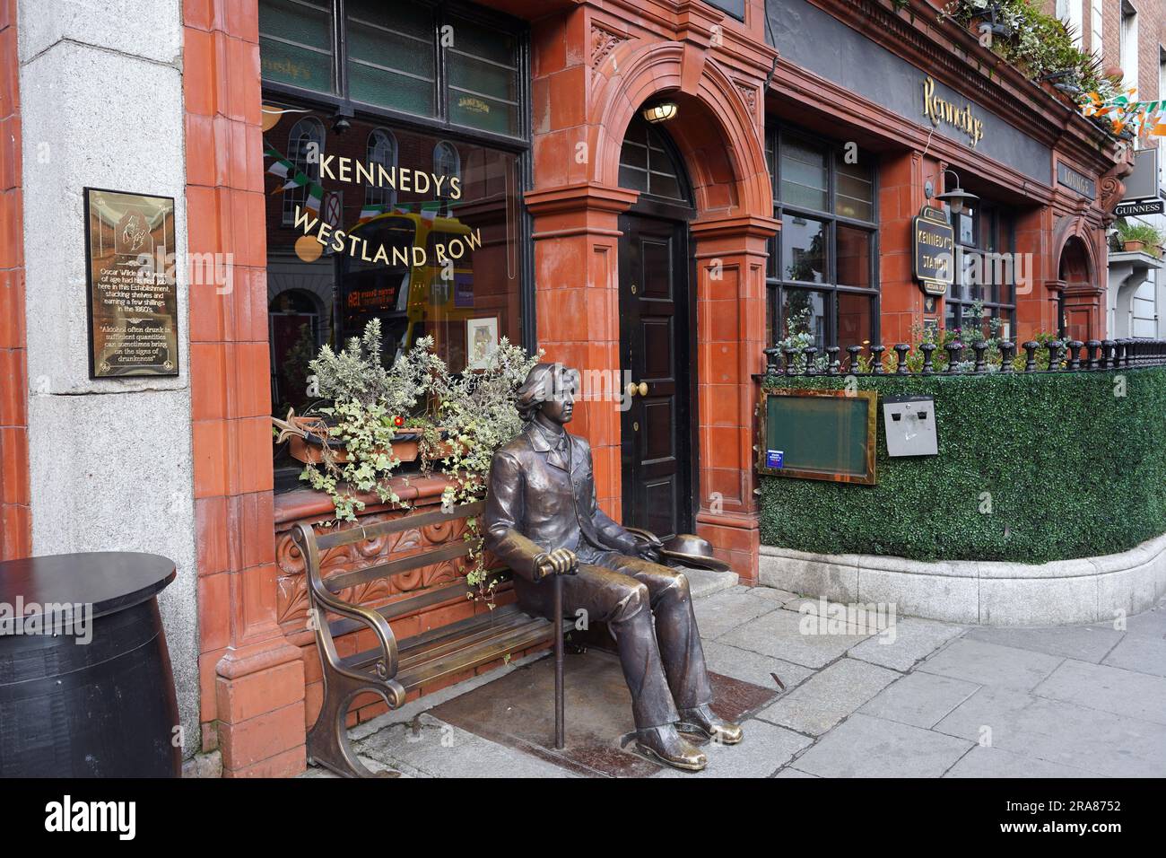 Statue d'Oscar Wilde assis sur un banc à l'extérieur d'un pub où il a travaillé comme adolescent Banque D'Images