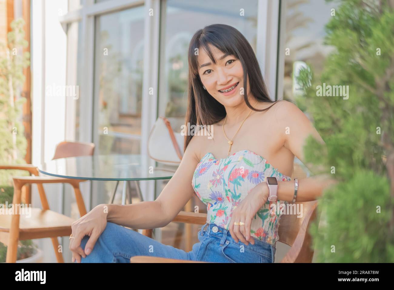 Portrait d'asiatique belle sexy femme asiatique assis souriant et relaxant portant une robe blanche sans bretelles et jupe jean dans un café Banque D'Images