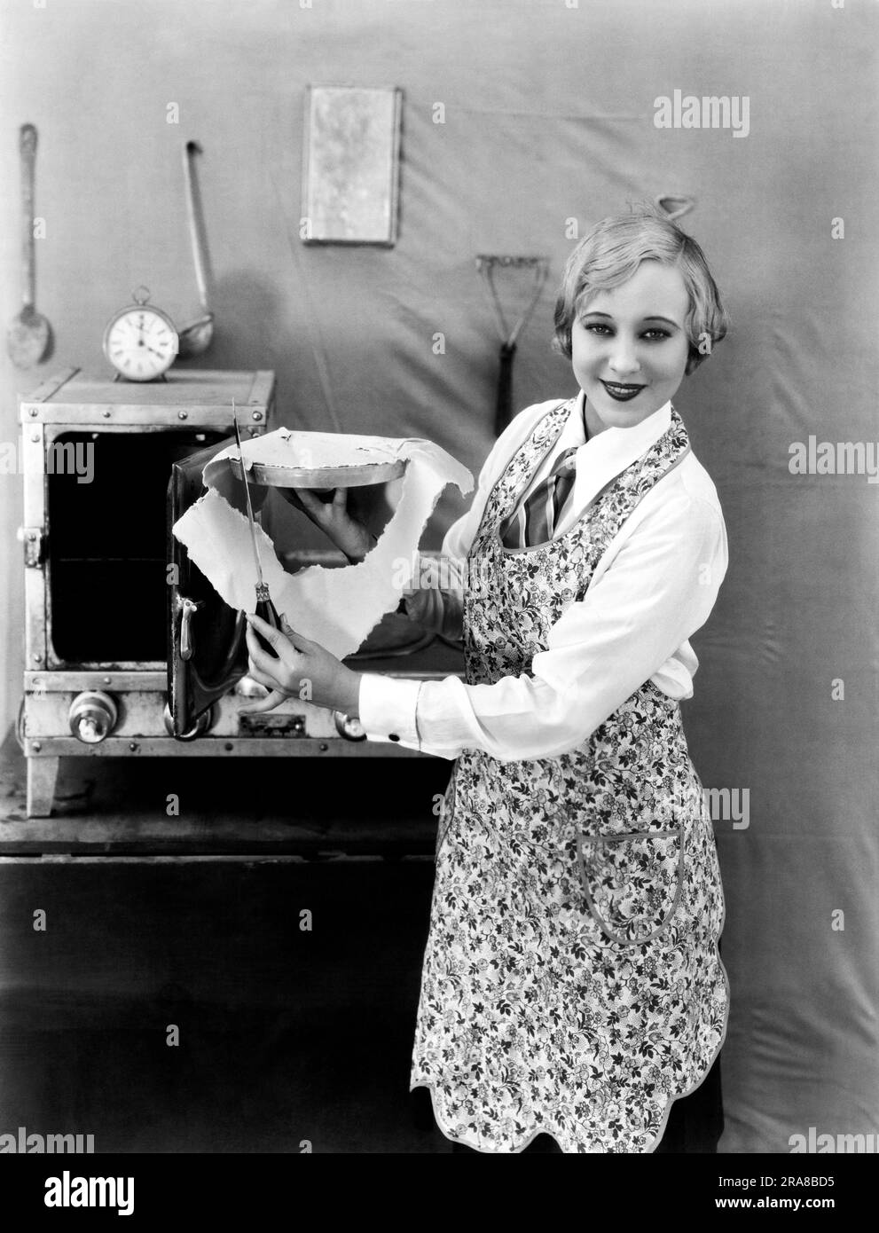 États-Unis : c. 1923. Une femme tond l'excédent de croûte d'une tarte avant de cuire. Banque D'Images