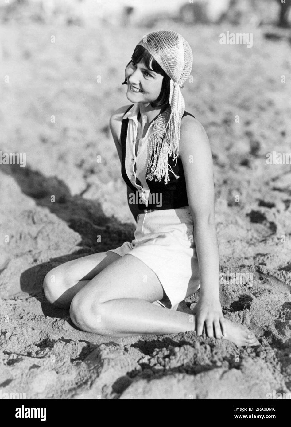 Los Angeles, Californie: c. 1929 Une jeune femme sur la plage de Venise portant le dernier vêtement de tête modish, la 'casquette tzigane', qui est faite d'un filet de soie. Banque D'Images