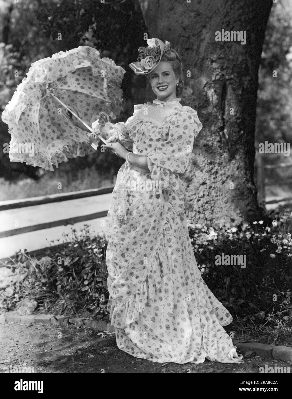 États-Unis: c. 1940 une jeune femme attrayante en robe victorienne tenant un parasol. Banque D'Images