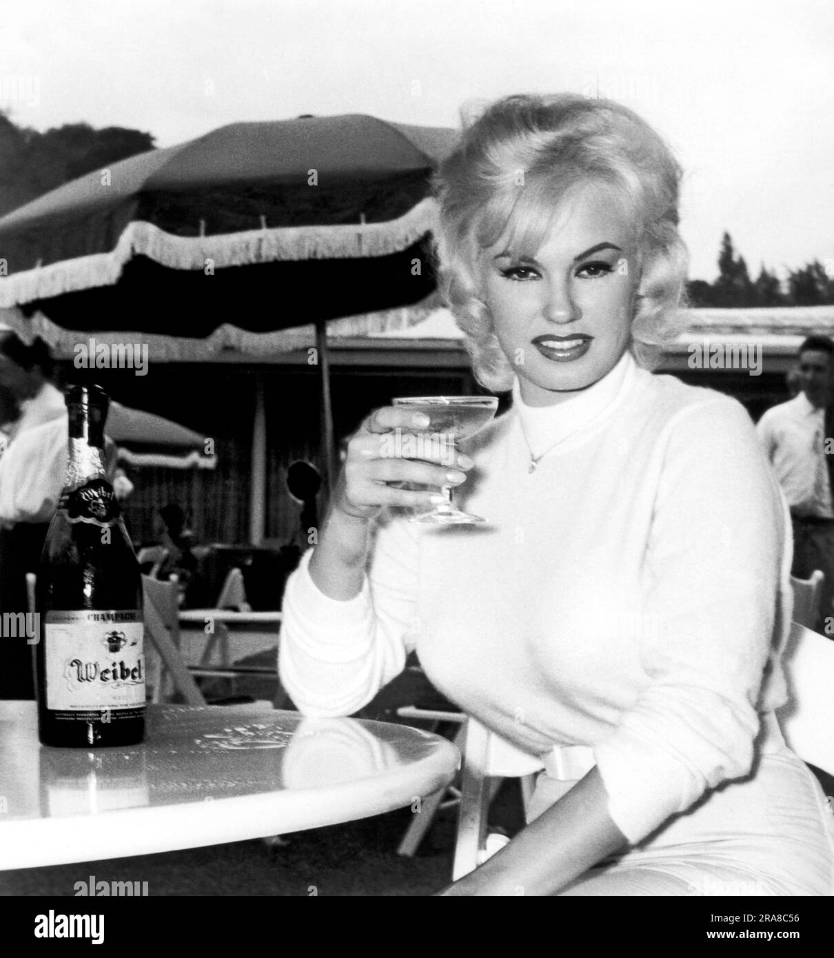 Hollywood, Californie : 1960. Le sultry Mamie Van Doren profite d'un verre de champagne lors d'un brunch hollywoodien en hommage à l'achèvement de la vie privée d'Adam et Eve, dans laquelle elle joue le rôle de titre de 'Eve'. Banque D'Images