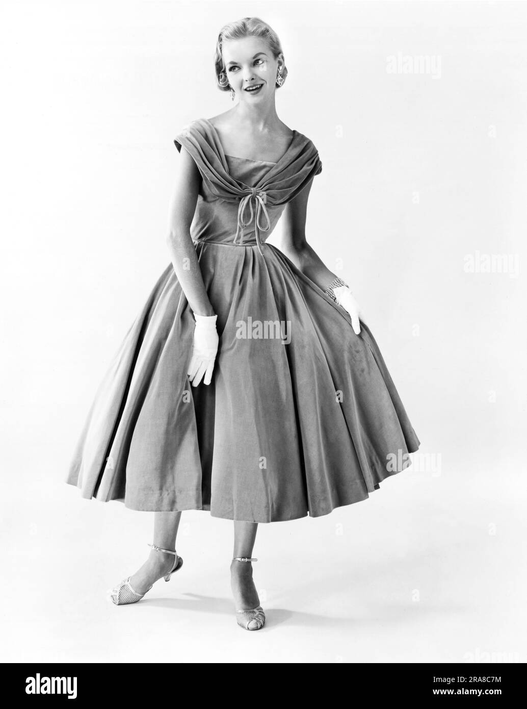 États-Unis : c. 1959 Une jeune femme à la mode qui se moque d'une robe de soirée. Banque D'Images