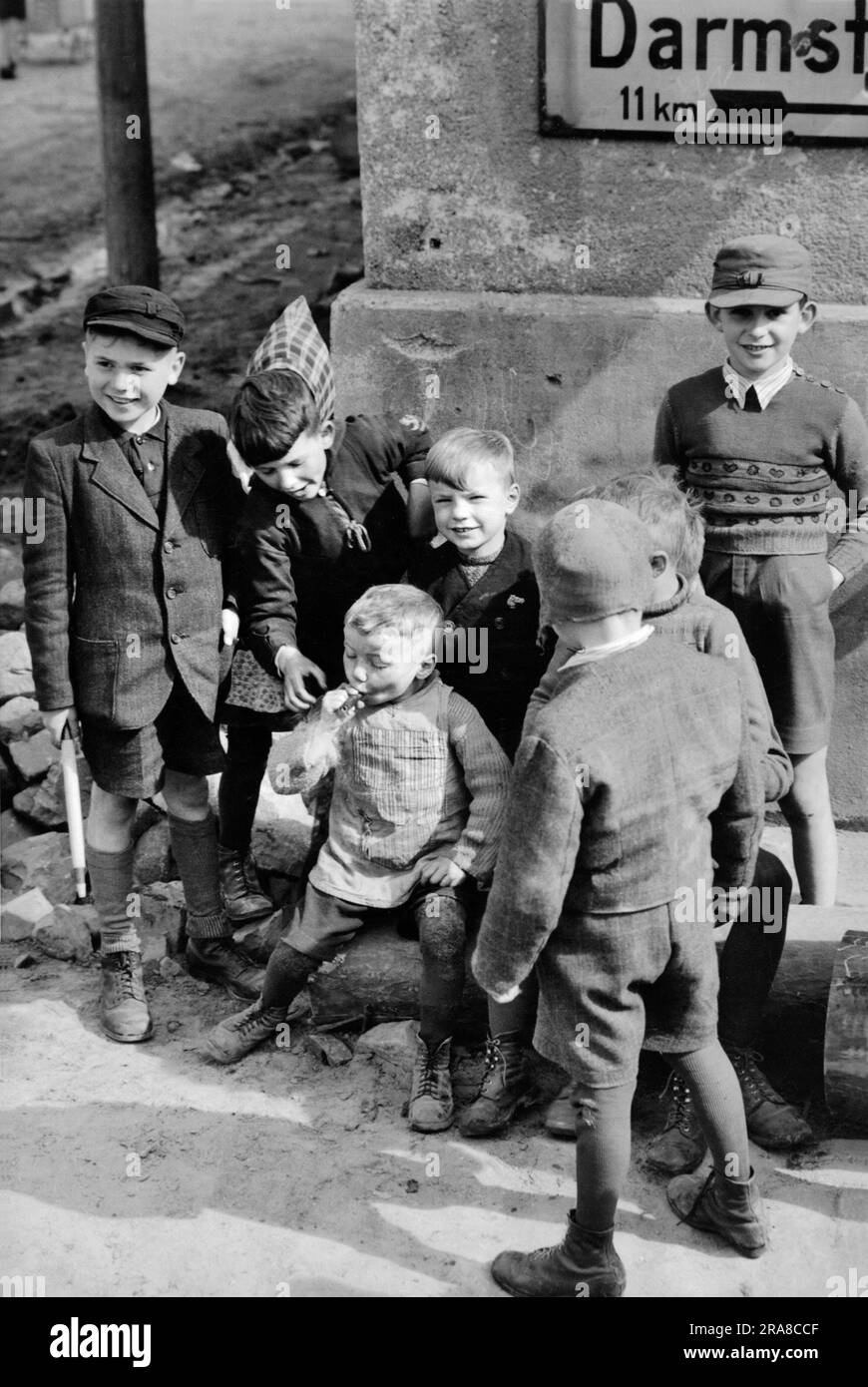 Buttelborn, Allemagne: 4 avril 1945 alors qu'un groupe de jeunes regarde, un garçon allemand de cinq ans souffle sur un cigare qui a été laissé tomber par un soldat des États-Unis Troisième armée en route vers Francfort. Banque D'Images