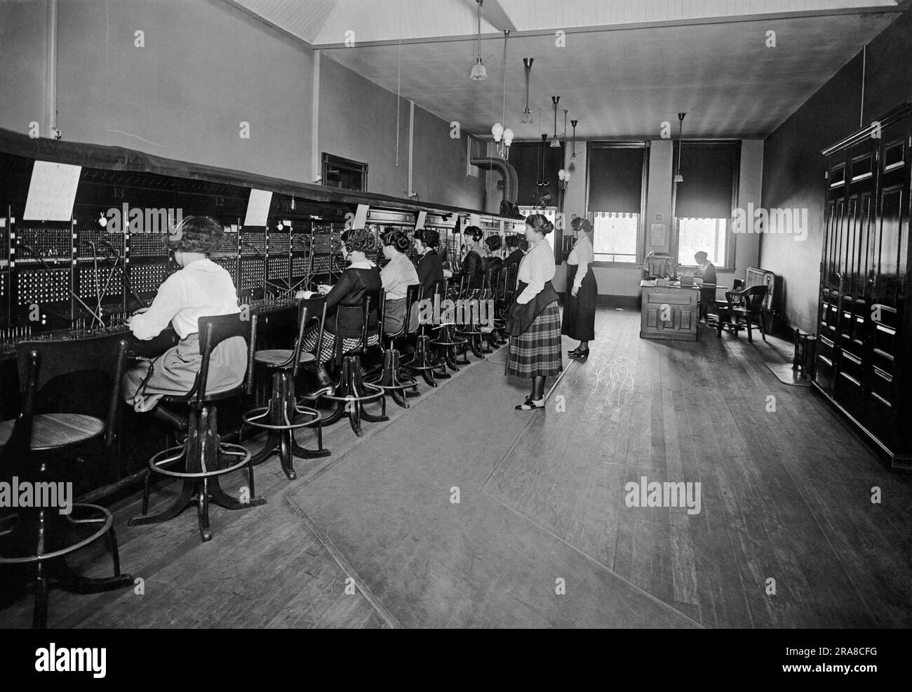 États-Unis, c. 1915 Un standard téléphonique avec des opérateurs reliant les appels et deux superviseurs à l'arrière et les supervisant. Banque D'Images