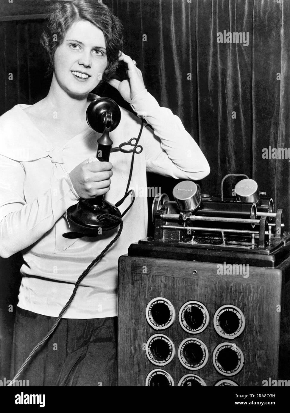 Chicago, Illinois : 13 novembre 1930 Une jeune femme présente la machine « Telfact » au salon national des affaires. Il enregistre les deux extrémités d'une conversation téléphonique sur les bouteilles de cire pour la postérité, les contrats et les poursuites judiciaires. Banque D'Images