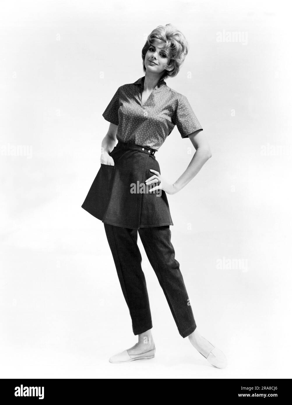 États-Unis: c. 1972 Une jeune femme mannequin Elizabeth Phelps pantalons denim avec une jupe enveloppante cousue à la ceinture. Un chemisier en coton imprimé calico ajoute de la couleur. Banque D'Images