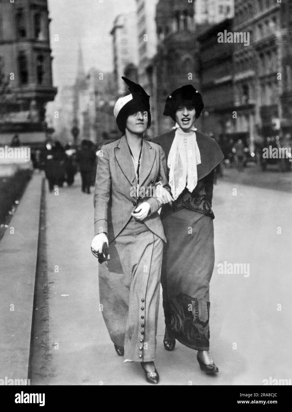 États-Unis : c. 1913 deux jeunes femmes à la mode qui descendent dans une rue de la ville. Banque D'Images