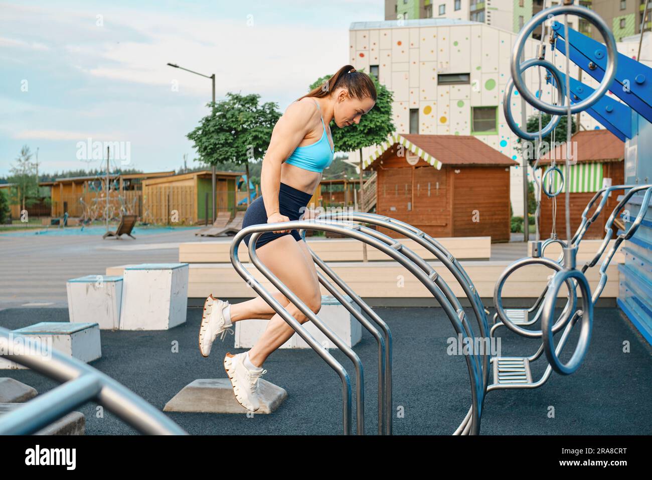Sportswoman effectuant des repoussez sur des barres irrégulières à l'extérieur Banque D'Images