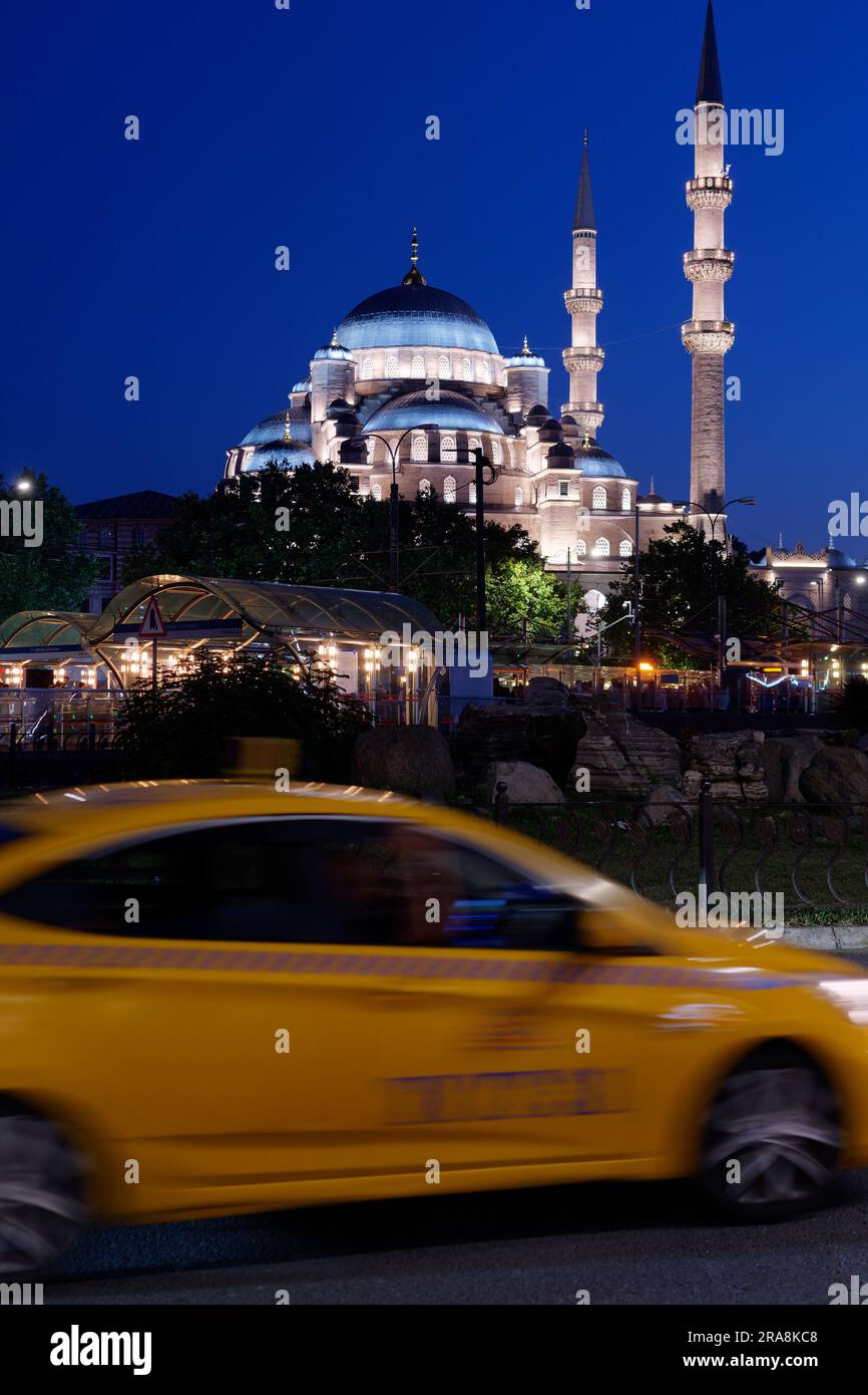 Mosquée Yeni Cami sur une nuit d'été avec un taxi jaune au premier plan flouté par le mouvement. Istanbul, Turquie Banque D'Images