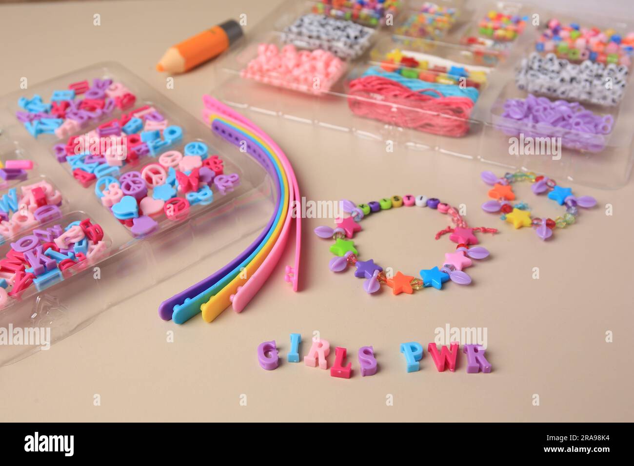 Kit de bijoux fait main pour les enfants. Perles colorées, bracelets et bracelets sur fond beige, gros plan Banque D'Images