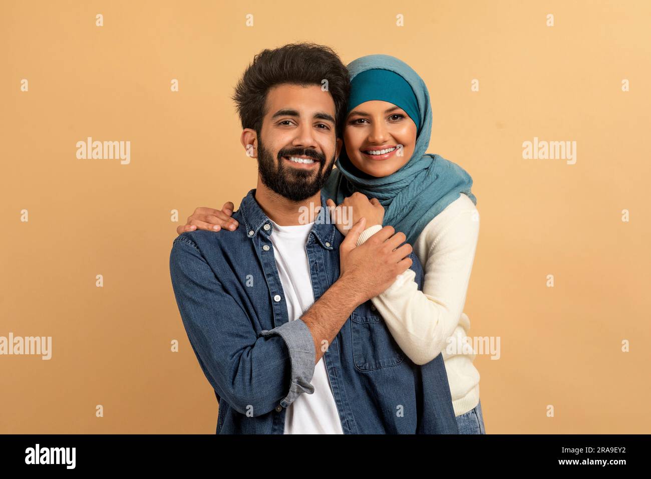 Portrait d'un couple musulman heureux embrassant sur fond beige Banque D'Images