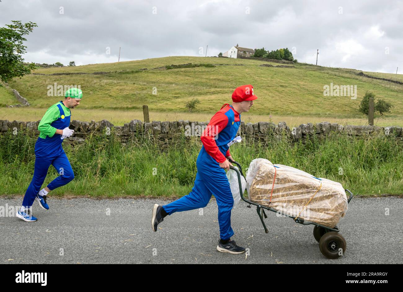 Les concurrents prennent part à la course de paille d'Oxenhope dans le West Yorkshire, une course de 2,5 kilomètres en costume fantaisie tout en portant une balle de paille de 20kg sur le trajet. Date de la photo: Dimanche 2 juillet 2023. La course a lieu chaque été dans le village Pennine d'Oxenhope, et a été lancé par deux hommes qui avaient un pari sur qui pourrait gagner une course d'un pub à l'autre portant une balle de paille. Le crédit photo devrait se lire comme suit : Danny Lawson/PA Wire Banque D'Images