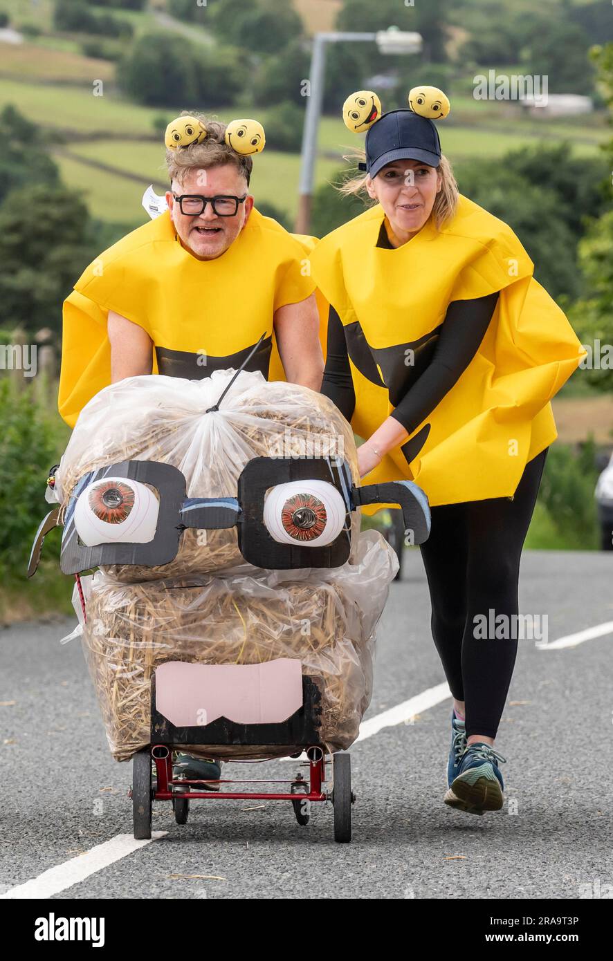 Les concurrents prennent part à la course de paille d'Oxenhope dans le West Yorkshire, une course de 2,5 kilomètres en costume fantaisie tout en portant une balle de paille de 20kg sur le trajet. Date de la photo: Dimanche 2 juillet 2023. La course a lieu chaque été dans le village Pennine d'Oxenhope, et a été lancé par deux hommes qui avaient un pari sur qui pourrait gagner une course d'un pub à l'autre portant une balle de paille. Le crédit photo devrait se lire comme suit : Danny Lawson/PA Wire Banque D'Images