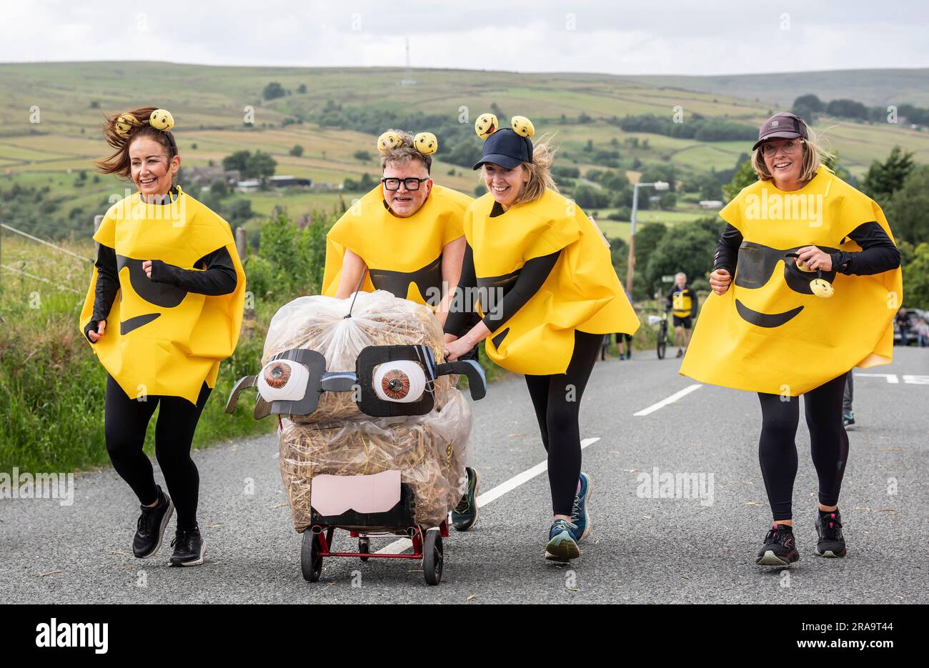 Les concurrents prennent part à la course de paille d'Oxenhope dans le West Yorkshire, une course de 2,5 kilomètres en costume fantaisie tout en portant une balle de paille de 20kg sur le trajet. Date de la photo: Dimanche 2 juillet 2023. La course a lieu chaque été dans le village Pennine d'Oxenhope, et a été lancé par deux hommes qui avaient un pari sur qui pourrait gagner une course d'un pub à l'autre portant une balle de paille. Le crédit photo devrait se lire comme suit : Danny Lawson/PA Wire Banque D'Images