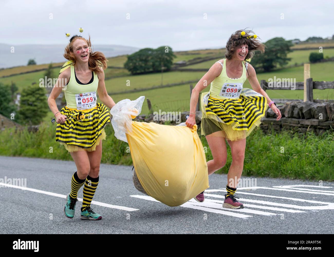 Les concurrents prennent part à la course de paille d'Oxenhope dans le West Yorkshire, une course de 2,5 kilomètres en costume fantaisie tout en portant une balle de paille de 20kg sur le trajet. Date de la photo: Dimanche 2 juillet 2023. La course a lieu chaque été dans le village Pennine d'Oxenhope, et a été lancé par deux hommes qui avaient un pari sur qui pourrait gagner une course d'un pub à l'autre portant une balle de paille. Le crédit photo devrait se lire comme suit : Danny Lawson/PA Wire Banque D'Images