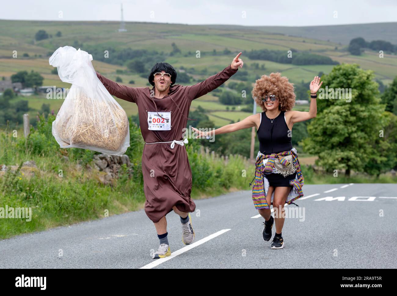 Les concurrents prennent part à la course de paille d'Oxenhope dans le West Yorkshire, une course de 2,5 kilomètres en costume fantaisie tout en portant une balle de paille de 20kg sur le trajet. Date de la photo: Dimanche 2 juillet 2023. La course a lieu chaque été dans le village Pennine d'Oxenhope, et a été lancé par deux hommes qui avaient un pari sur qui pourrait gagner une course d'un pub à l'autre portant une balle de paille. Le crédit photo devrait se lire comme suit : Danny Lawson/PA Wire Banque D'Images