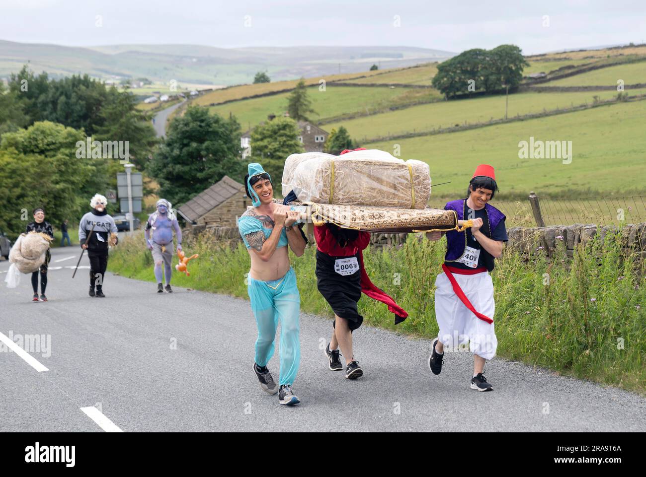 Les concurrents prennent part à la course de paille d'Oxenhope dans le West Yorkshire, une course de 2,5 kilomètres en costume fantaisie tout en portant une balle de paille de 20kg sur le trajet. Date de la photo: Dimanche 2 juillet 2023. La course a lieu chaque été dans le village Pennine d'Oxenhope, et a été lancé par deux hommes qui avaient un pari sur qui pourrait gagner une course d'un pub à l'autre portant une balle de paille. Le crédit photo devrait se lire comme suit : Danny Lawson/PA Wire Banque D'Images