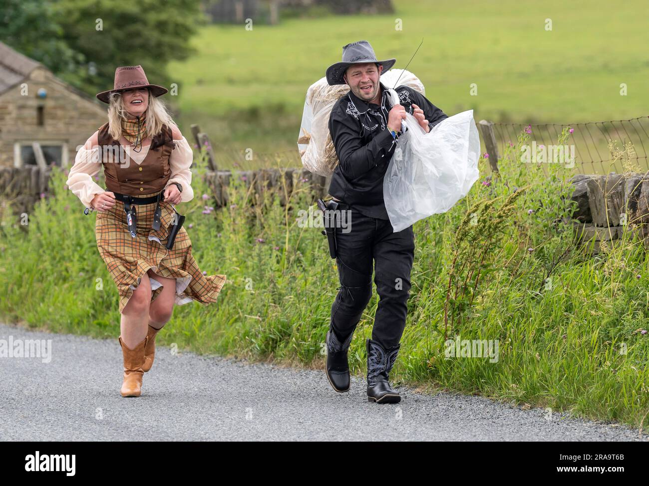 Les concurrents prennent part à la course de paille d'Oxenhope dans le West Yorkshire, une course de 2,5 kilomètres en costume fantaisie tout en portant une balle de paille de 20kg sur le trajet. Date de la photo: Dimanche 2 juillet 2023. La course a lieu chaque été dans le village Pennine d'Oxenhope, et a été lancé par deux hommes qui avaient un pari sur qui pourrait gagner une course d'un pub à l'autre portant une balle de paille. Le crédit photo devrait se lire comme suit : Danny Lawson/PA Wire Banque D'Images