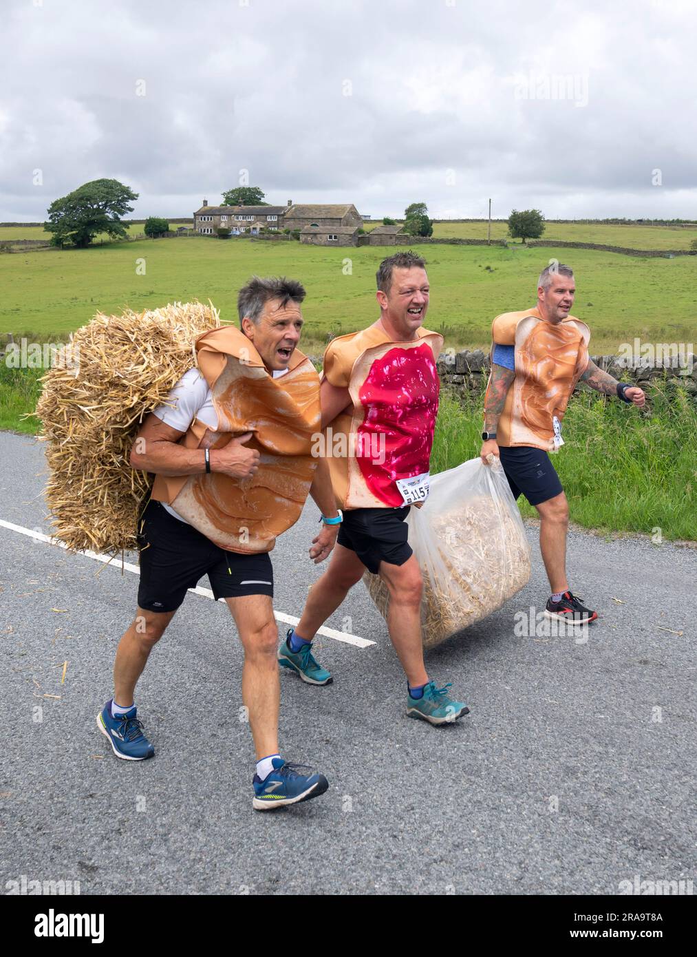 Les concurrents prennent part à la course de paille d'Oxenhope dans le West Yorkshire, une course de 2,5 kilomètres en costume fantaisie tout en portant une balle de paille de 20kg sur le trajet. Date de la photo: Dimanche 2 juillet 2023. La course a lieu chaque été dans le village Pennine d'Oxenhope, et a été lancé par deux hommes qui avaient un pari sur qui pourrait gagner une course d'un pub à l'autre portant une balle de paille. Le crédit photo devrait se lire comme suit : Danny Lawson/PA Wire Banque D'Images