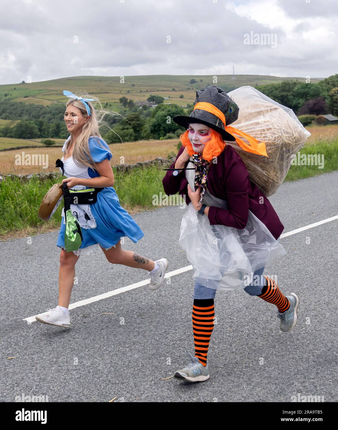 Les concurrents prennent part à la course de paille d'Oxenhope dans le West Yorkshire, une course de 2,5 kilomètres en costume fantaisie tout en portant une balle de paille de 20kg sur le trajet. Date de la photo: Dimanche 2 juillet 2023. La course a lieu chaque été dans le village Pennine d'Oxenhope, et a été lancé par deux hommes qui avaient un pari sur qui pourrait gagner une course d'un pub à l'autre portant une balle de paille. Le crédit photo devrait se lire comme suit : Danny Lawson/PA Wire Banque D'Images