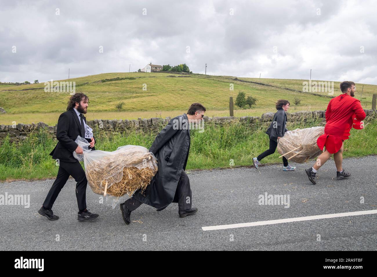 Les concurrents prennent part à la course de paille d'Oxenhope dans le West Yorkshire, une course de 2,5 kilomètres en costume fantaisie tout en portant une balle de paille de 20kg sur le trajet. Date de la photo: Dimanche 2 juillet 2023. La course a lieu chaque été dans le village Pennine d'Oxenhope, et a été lancé par deux hommes qui avaient un pari sur qui pourrait gagner une course d'un pub à l'autre portant une balle de paille. Le crédit photo devrait se lire comme suit : Danny Lawson/PA Wire Banque D'Images
