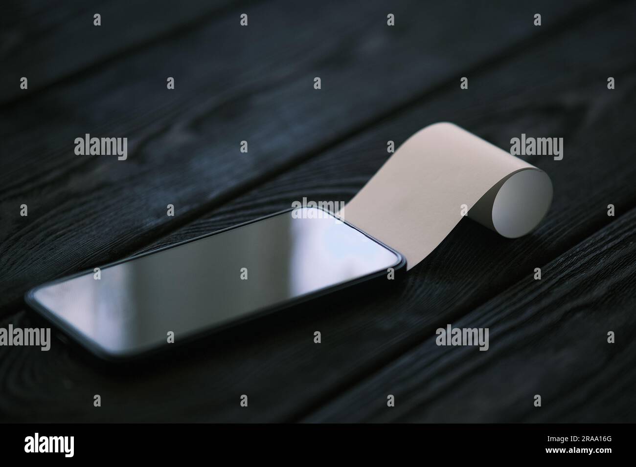 Un téléphone portable avec un chèque vierge sur une table en bois noir, concept financier Banque D'Images