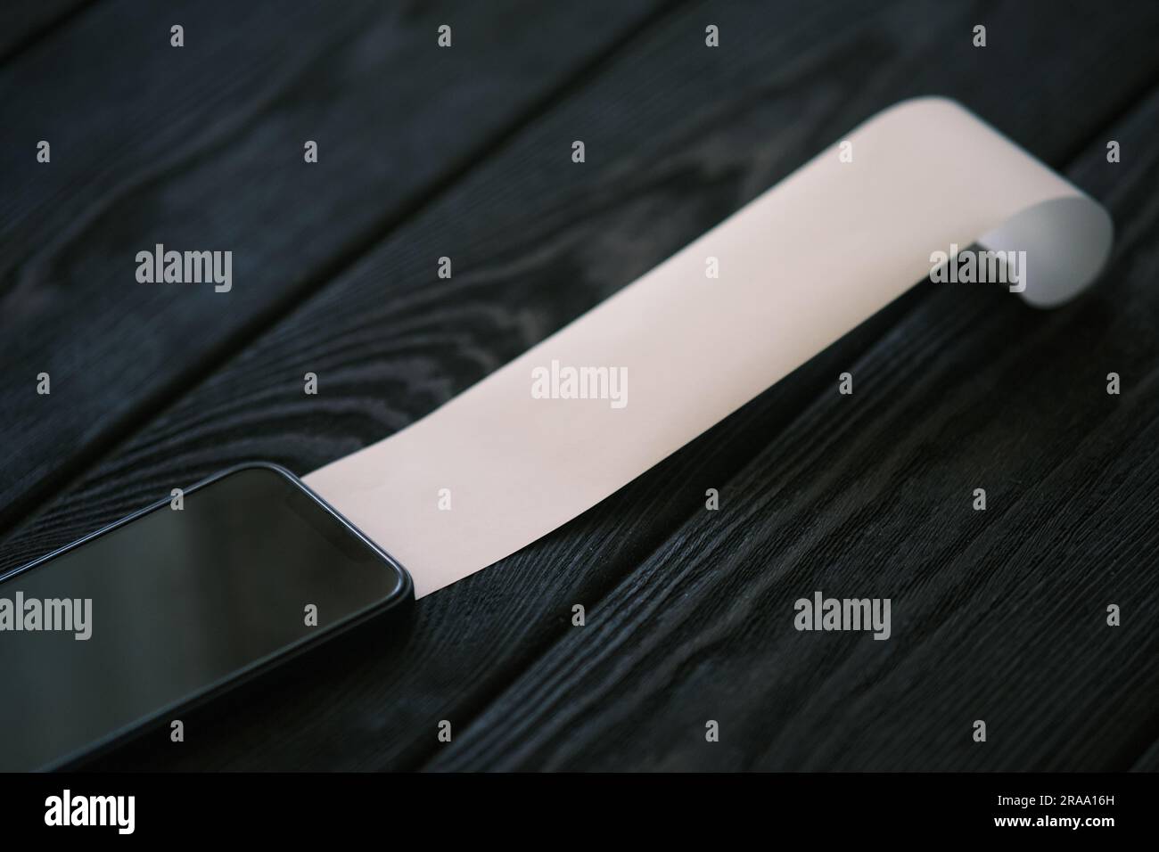 Un téléphone portable avec un chèque vierge sur une table en bois noir, concept financier Banque D'Images
