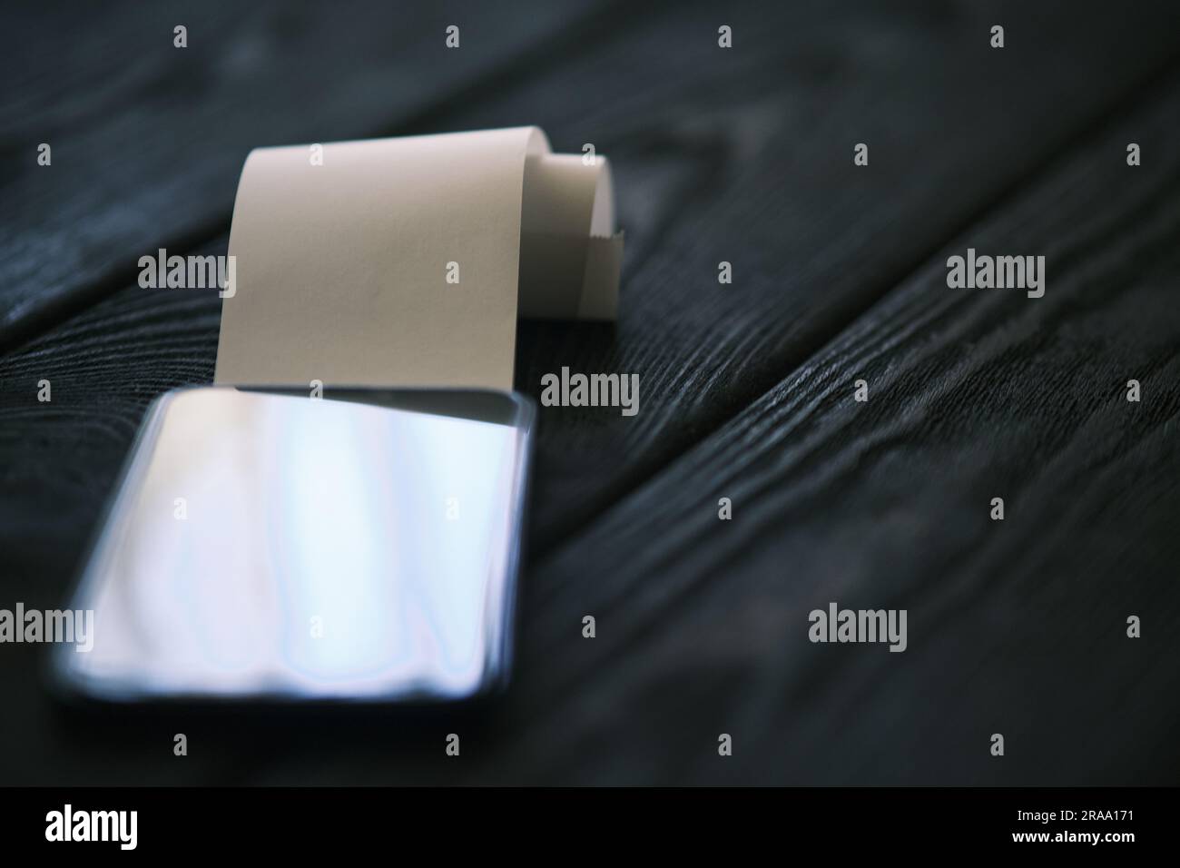 Un téléphone portable avec un chèque vierge sur une table en bois noir, concept financier Banque D'Images