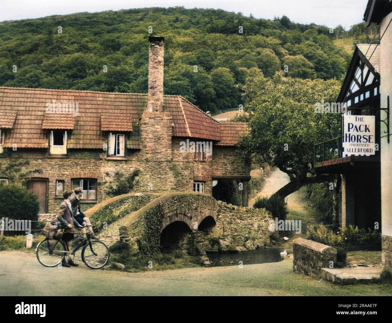 L'ancien pont à cheval à dos de cartel à Allerford, Somerset. La combinaison du pont, de l'ancienne auberge, des cottages avec des toits pittoresques et des cheminées, en font un charmant village de campagne de l'Ouest. Date: 1940s Banque D'Images