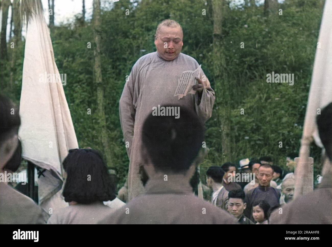 Lors d'une rencontre anti-communiste à Wukiang, de jeunes et d'étudiants, le magistrat local, portant la longue robe traditionnelle, prononce un discours. Date: 1939 Banque D'Images