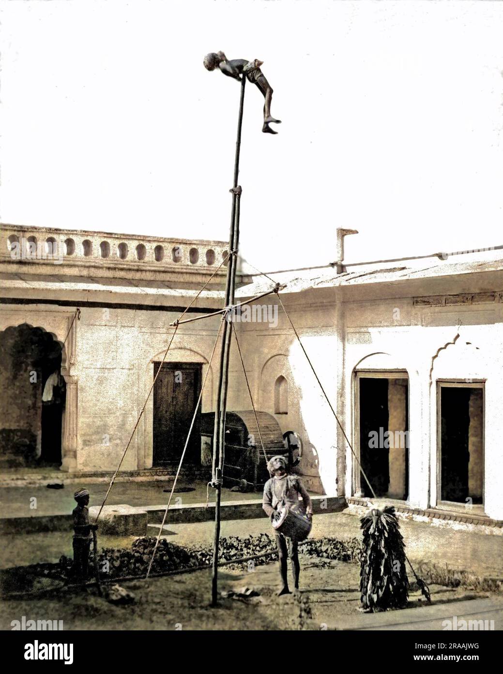 Un acrobat au sommet d'un poteau, avec un batteur en dessous, Inde. Date: Vers 1890s Banque D'Images