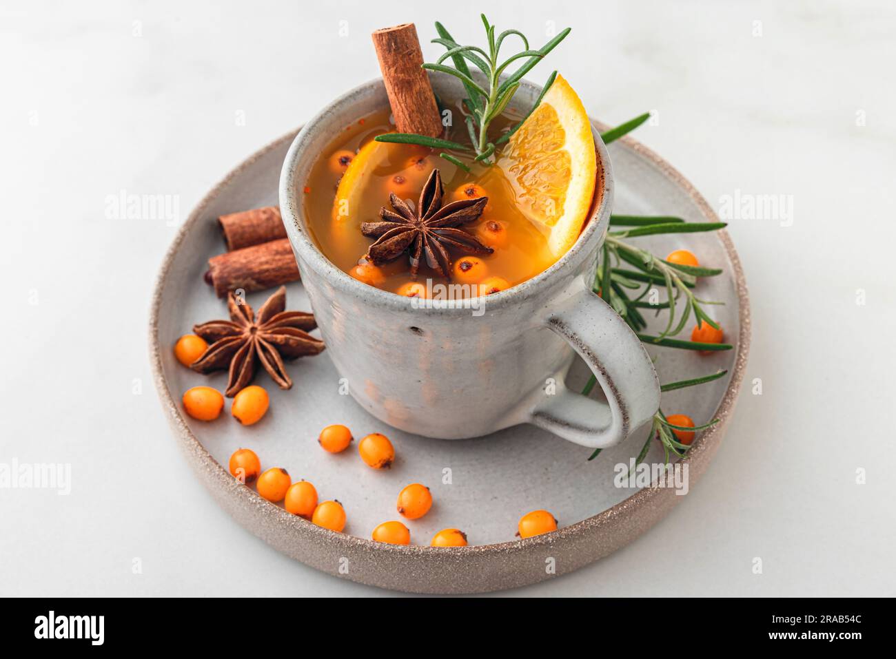 Tasse de thé d'argousier avec orange, baies, cannelle et romarin sur table blanche. Gros plan. Boisson saine à base de plantes Banque D'Images