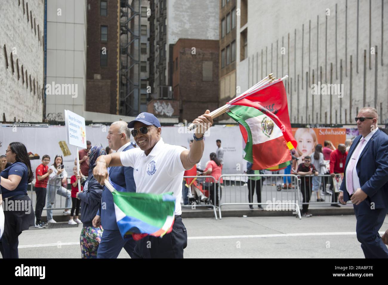 Le maire Eric Adams marche dans la parade des immigrants portant divers drapeaux internationaux représentant diverses communautés immigrées qui font partie du tissu qui composent la ville de New York. Banque D'Images