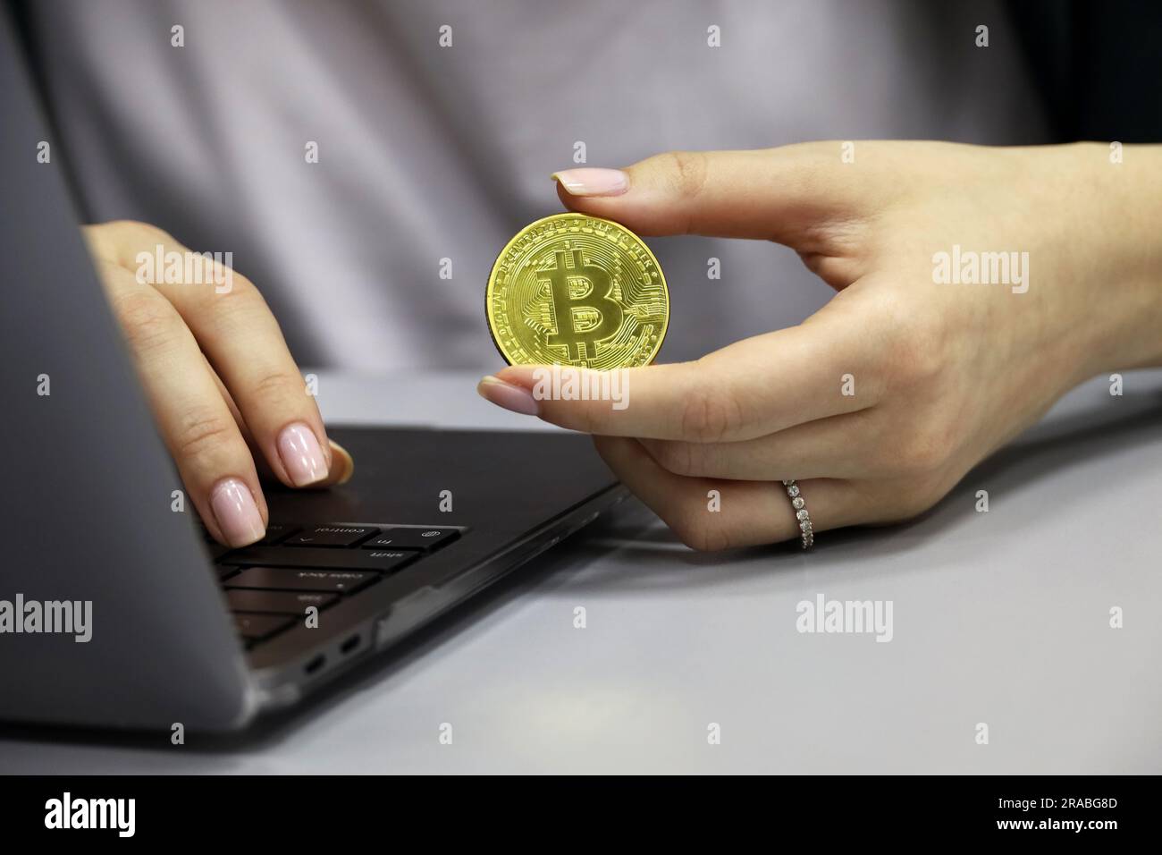 Bitcoin entre les mains d'une fille qui travaille à un ordinateur portable. Monnaie électronique décentralisée, crypto-monnaie Banque D'Images