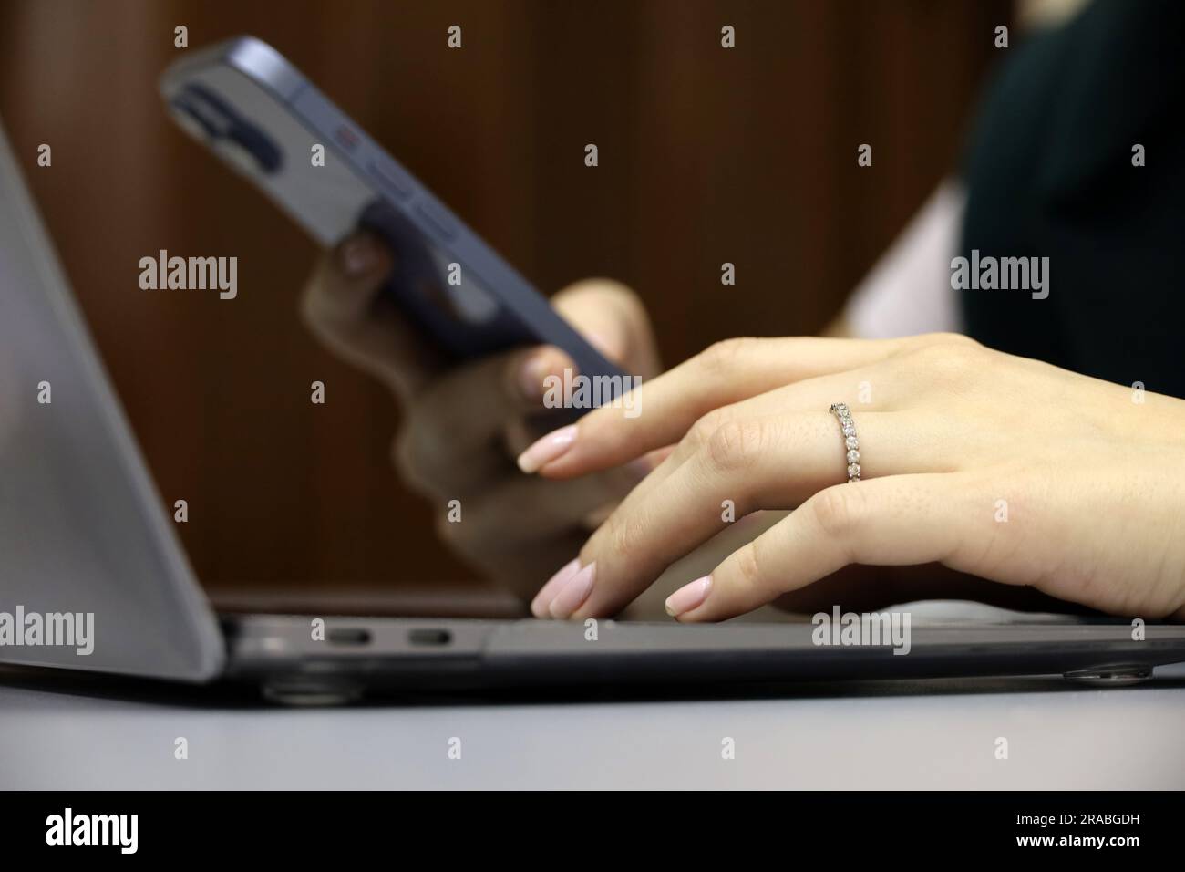 Femme utilisant un smartphone sur l'arrière-plan du clavier de l'ordinateur portable, mise au point sélective sur la main femelle gauche. Concept de communication, de travail et de paiement en ligne Banque D'Images