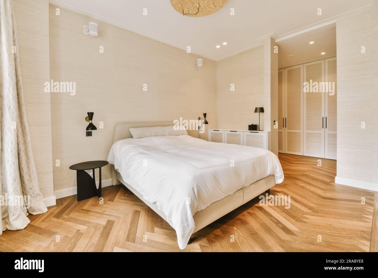 une chambre avec parquet et draps blancs sur le lit, il y a une grande fenêtre dans la chambre Banque D'Images