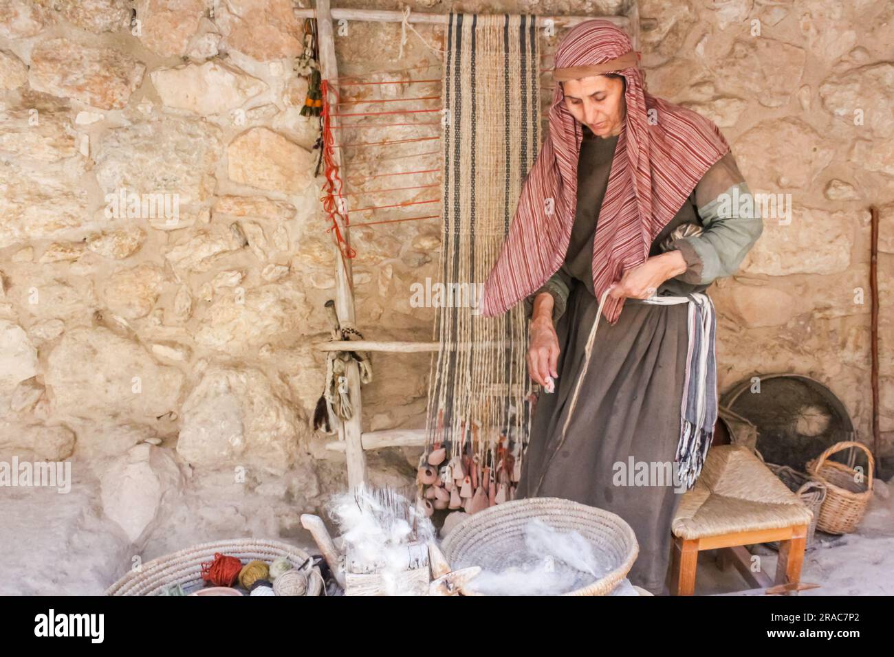 Hannah le Weaver présente une femme du premier siècle qui prépare la laine à être tissée au musée en plein air du village de Nazareth, en Israël. Banque D'Images