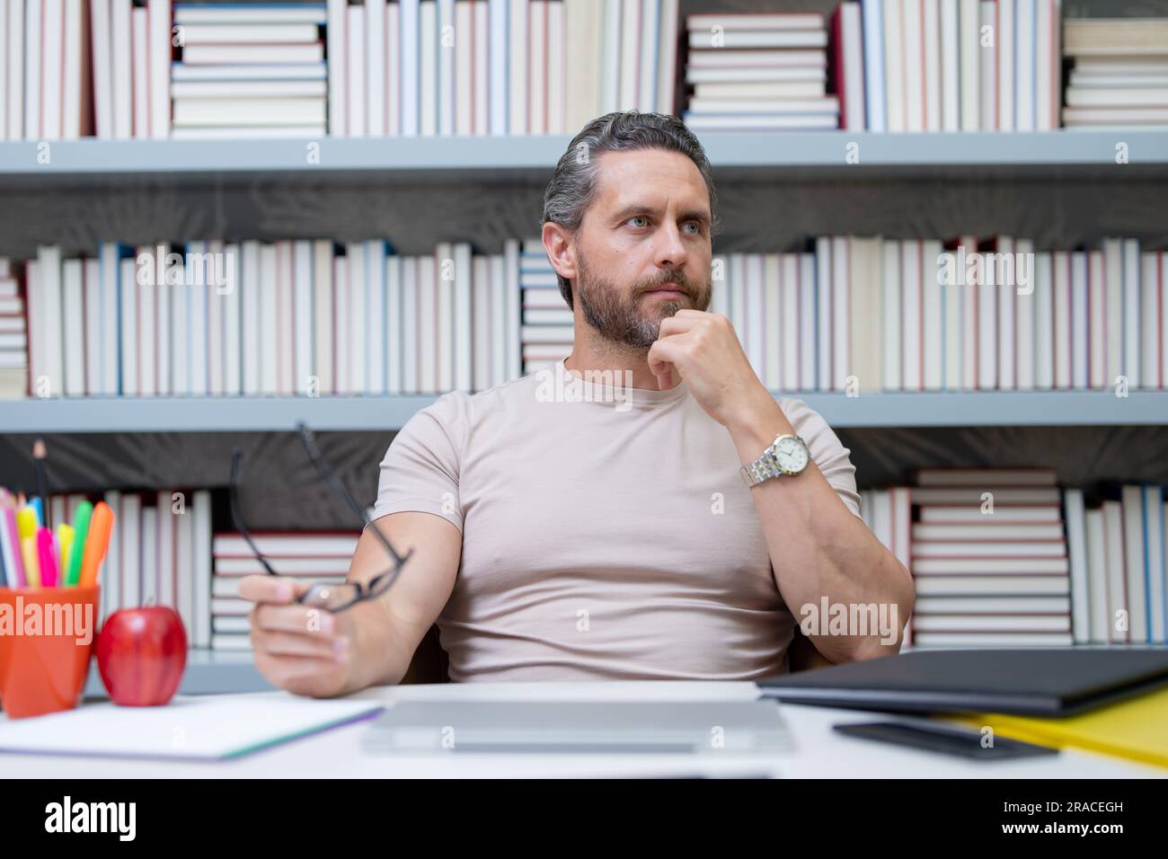 Journée des enseignants. Enseignant en classe scolaire. Connaissance et éducation avec un enseignant d'âge moyen. Professeur hispanique avec livre. Leçon d'enseignement de l'homme en classe. Banque D'Images