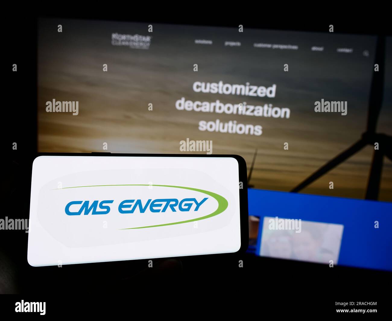 Personne tenant le téléphone portable avec le logo de la société de services publics américaine CMS Energy Corporation sur l'écran en face de la page Web de l'entreprise. Concentrez-vous sur l'affichage du téléphone. Banque D'Images