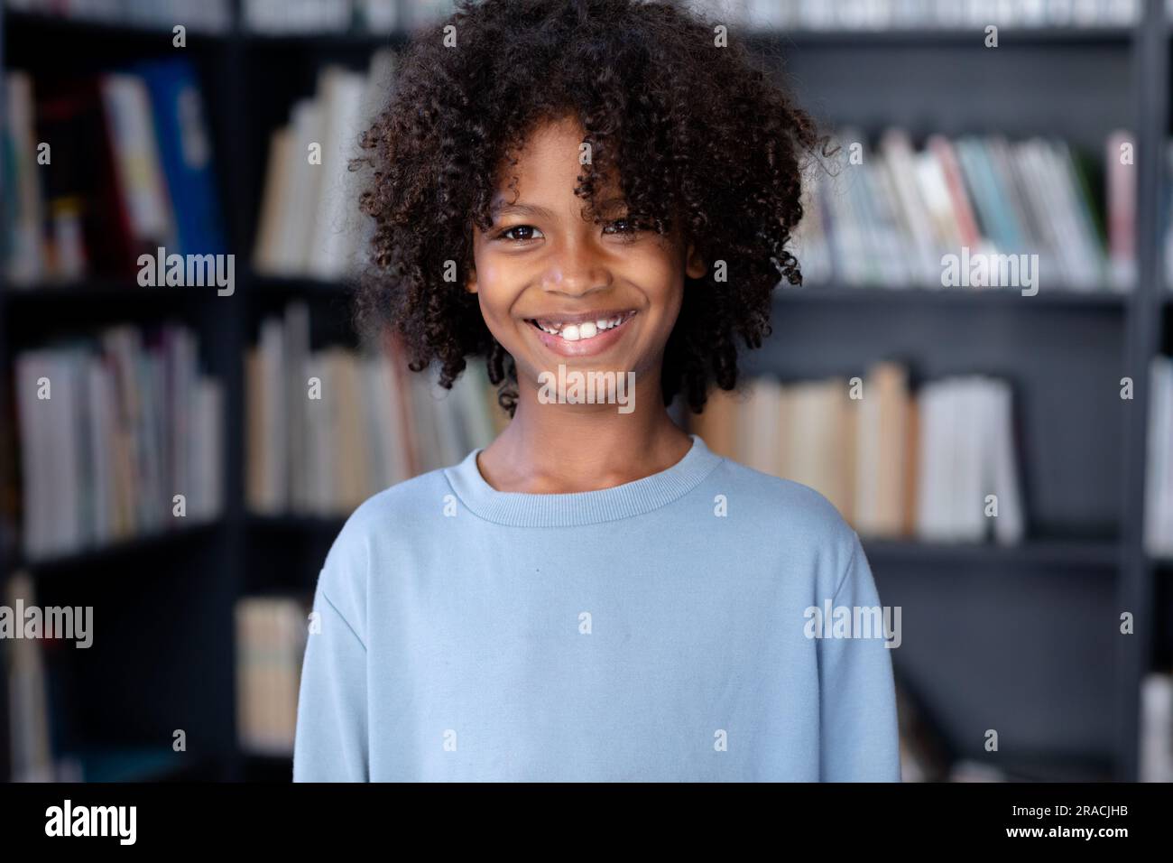 Écolier afro-américain portant un t-shirt bleu à manches longues avec Copyspace au-dessus de la bibliothèque Banque D'Images